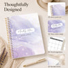 A5 monthly planner with purple marble design and gold spiral binding shown next to a pen.