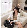 A woman is using a compact black portable water bottle on a sofa.