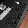 A black leopard print non-slip gaming mouse pad with a white computer mouse and keyboard visible on a dark surface.