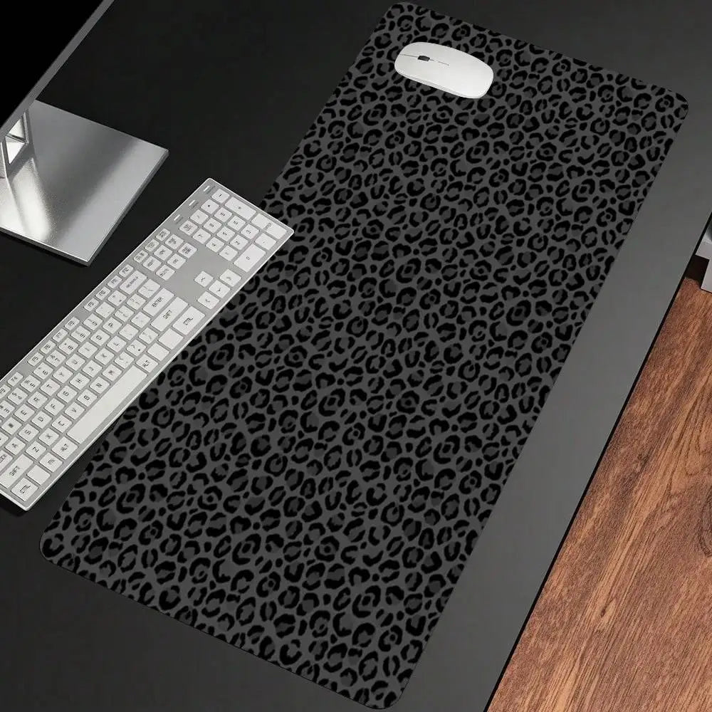 A black leopard print non-slip gaming mouse pad with a white computer mouse and keyboard visible on a dark surface.