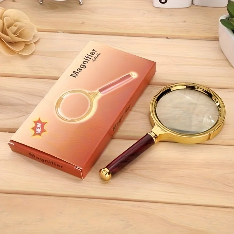 A new magnifying glass in a brown box rests on a wooden surface.
