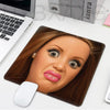 A realistic doll face sculpture of a woman with brown hair is displayed on a leather mouse pad.