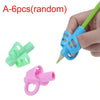 A set of six random silicone pencil grips including green and pink shapes being held by a hand