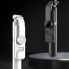 A white Bluetooth selfie stick with an LED fill light and tripod stand displayed against a dark background.