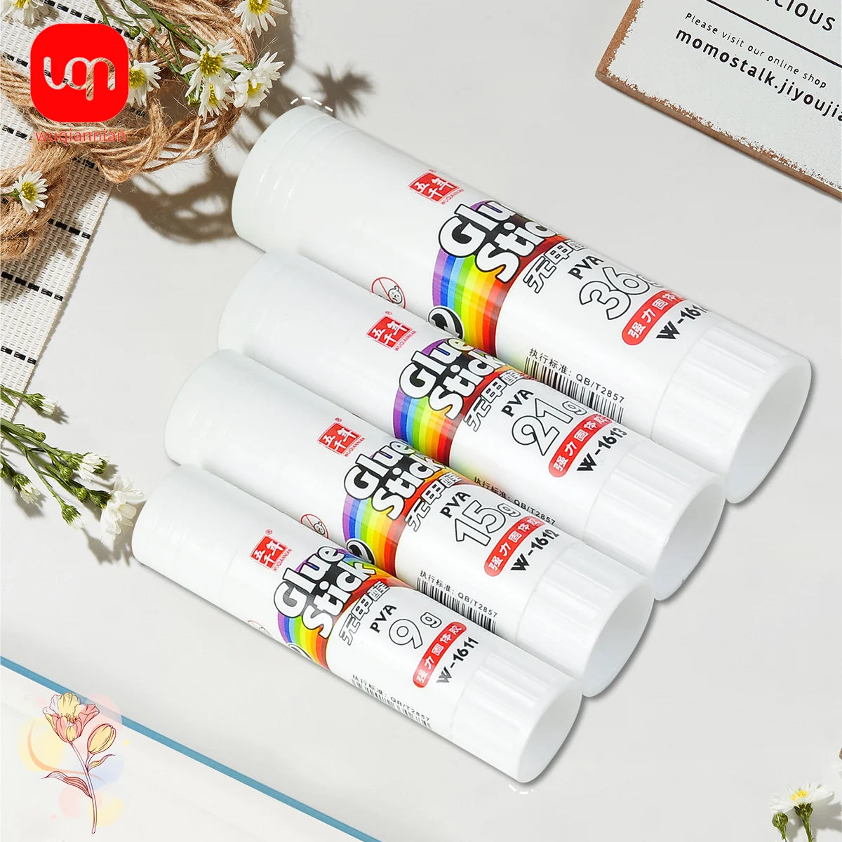 A collection of white glue sticks with rainbow colored tips and various pack sizes displayed on a white surface.