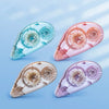 Three clear adhesive tapes in blue, pink, and purple shades are shown at an angle on a light blue background.