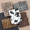 A collection of leopard print binders and folders in various shades of brown, black, and white.