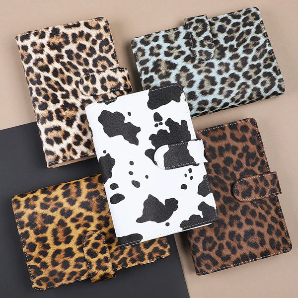A collection of leopard print binders and folders in various shades of brown, black, and white.