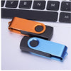 A close-up of two colorful metal USB flash drives resting on a white laptop keyboard.
