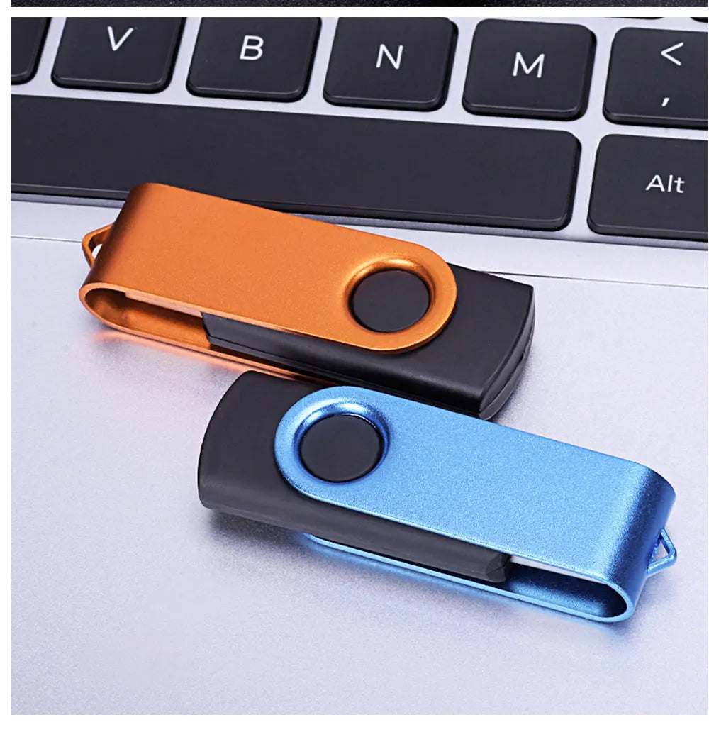 A close-up of two colorful metal USB flash drives resting on a white laptop keyboard.