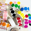 A collection of round dot labels in various colors including green, yellow, pink, and blue, arranged on a white background.