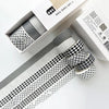 A set of six rolls of plaid, grid, and polka dot washi tape in black and white patterns displayed in its packaging.