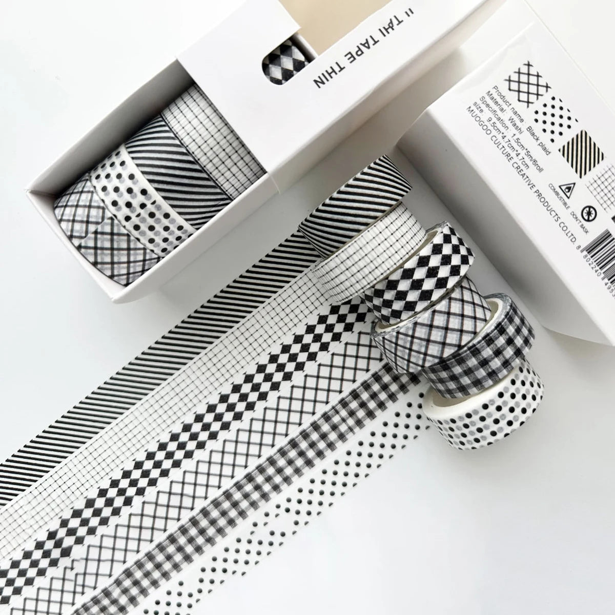 A set of six rolls of plaid, grid, and polka dot washi tape in black and white patterns displayed in its packaging.