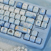 A close-up view of blue sea themed PBT keycaps for a mechanical keyboard arranged in a tray.