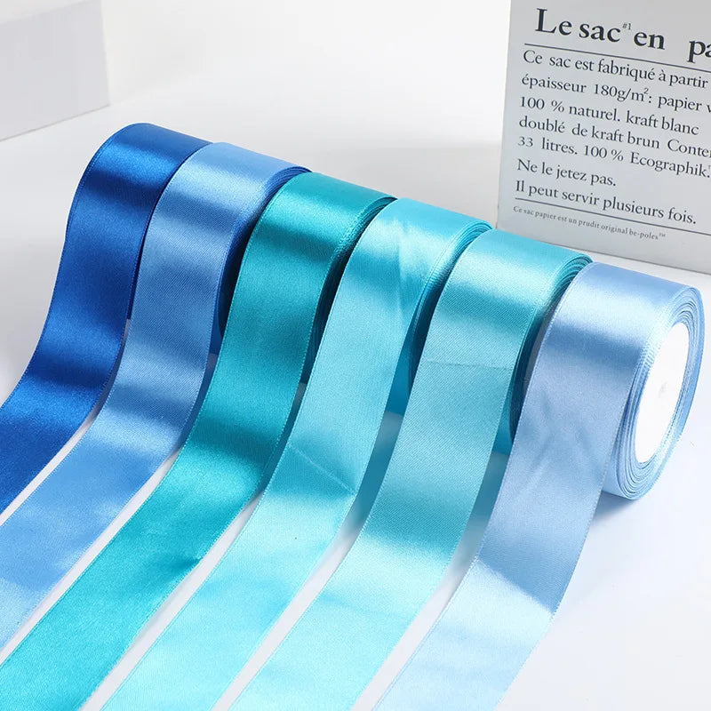 Roll of satin ribbon in various shades of blue and teal for gift wrapping or crafts