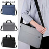 A person is carrying a gray nylon laptop tote bag with black straps over their shoulder.