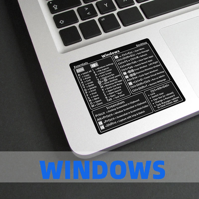 A close-up of a laptop keyboard showing a Windows shortcut quick reference sticker for various keyboard commands.