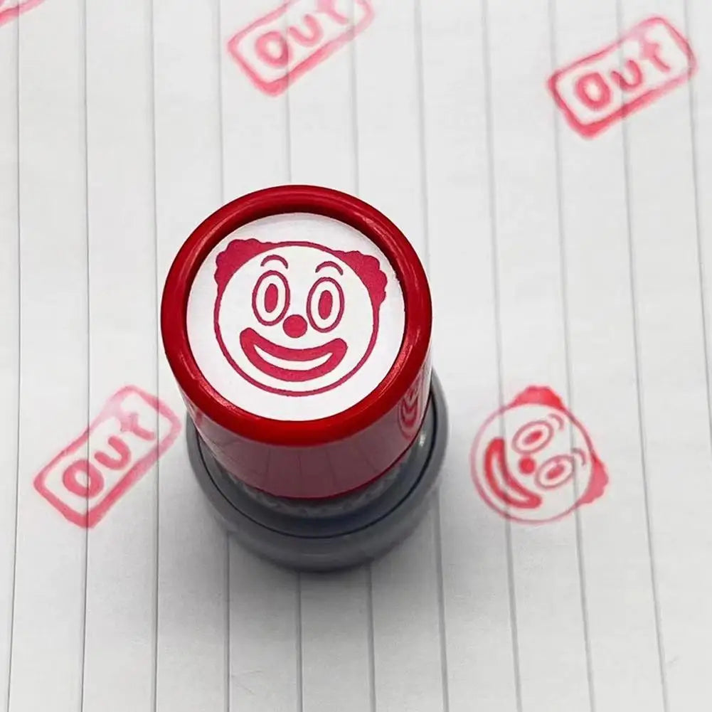 A red rubber stamp with a funny meme face design is shown on a white surface.