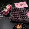 A pink mechanical keyboard with a knob is displayed on a dark surface next to roses and a cup of coffee.
