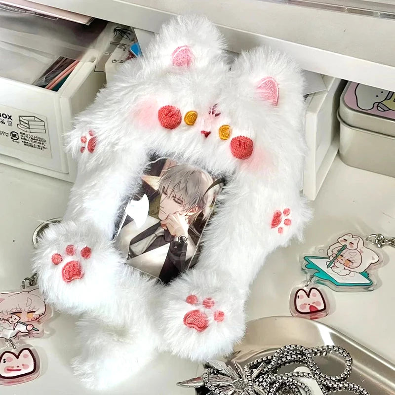 A white fluffy plush holder designed to display a K-pop photocard, featuring pink paw prints and small decorative elements.