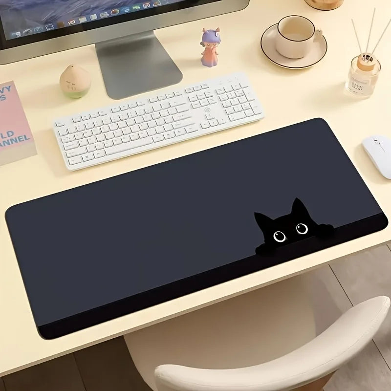 A dark gray mouse pad featuring a silhouette of a black cat on a light wooden desk with a laptop and keyboard.