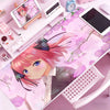 A pink anime character illustration on a large pink mouse pad with floral designs, next to a white mouse and clock.