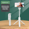 A white mobile phone holder tripod with an LED fill light and Bluetooth remote is displayed on a wooden table.