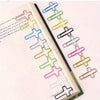 A collection of cross-shaped metal paper clips in various colors arranged along the edge of a book page.