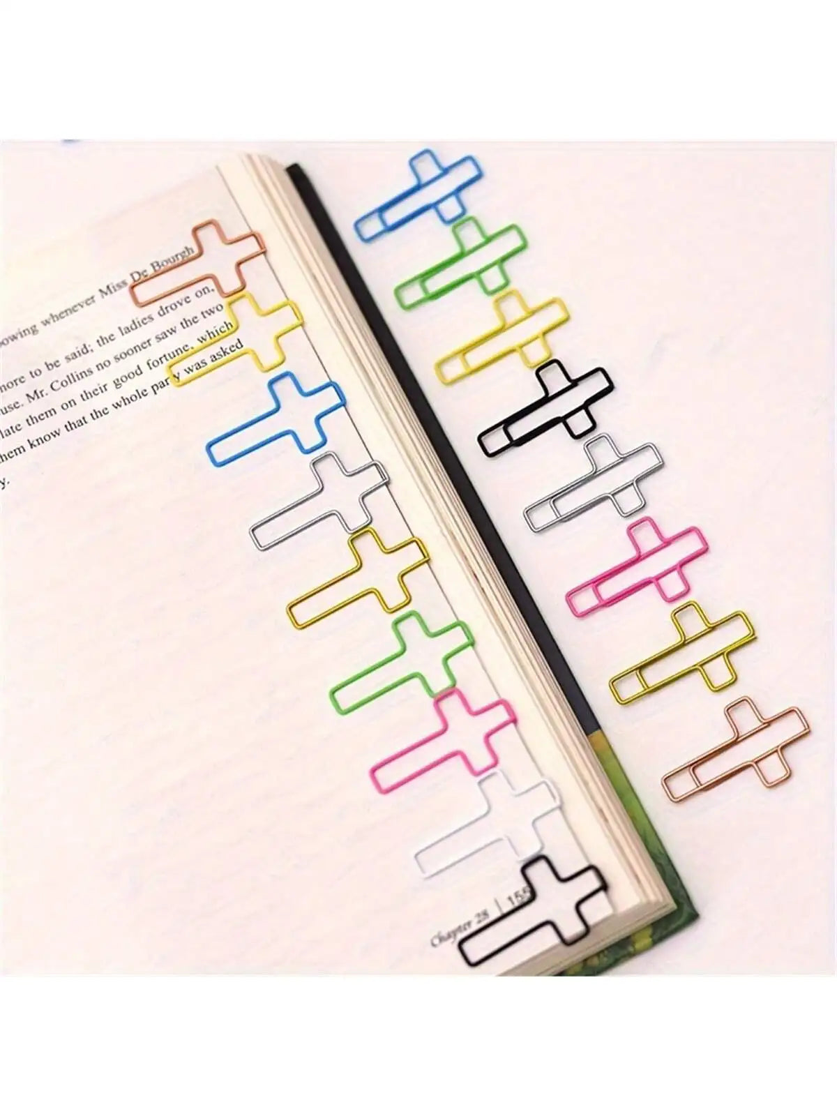 A collection of cross-shaped metal paper clips in various colors arranged along the edge of a book page.