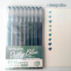 A set of nine Dusty Blue gel pens in a clear plastic case and accompanying notebook.