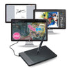 A professional graphic digital drawing tablet with a stylus and multiple monitors is shown on a desk.