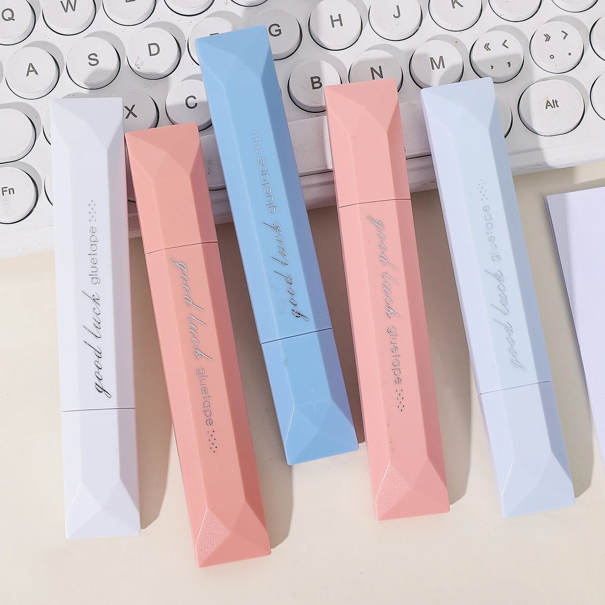 A collection of five gradient double-sided tape pens in various shades of pink and blue resting on a keyboard.