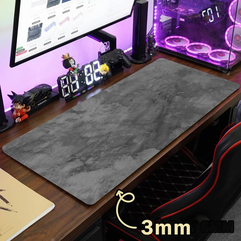 Gray overlocked mouse pad placed on a wooden desk next to a monitor and gaming setup.