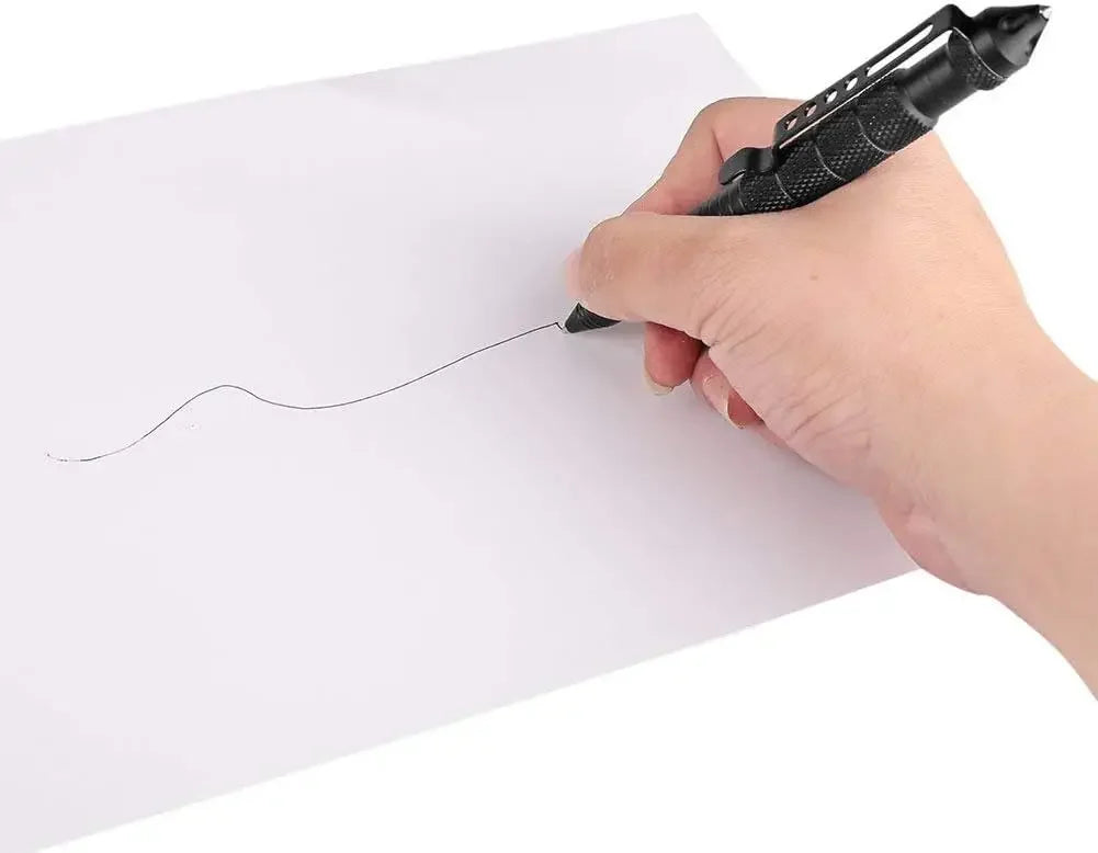 A hand is using a black tactical self-defense pen with a glass breaker tip to draw a line on a white piece of paper.