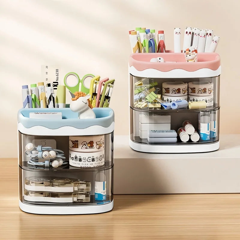 A clear acrylic desktop pen holder with pink accents holds various pens, pencils, and stationery items.