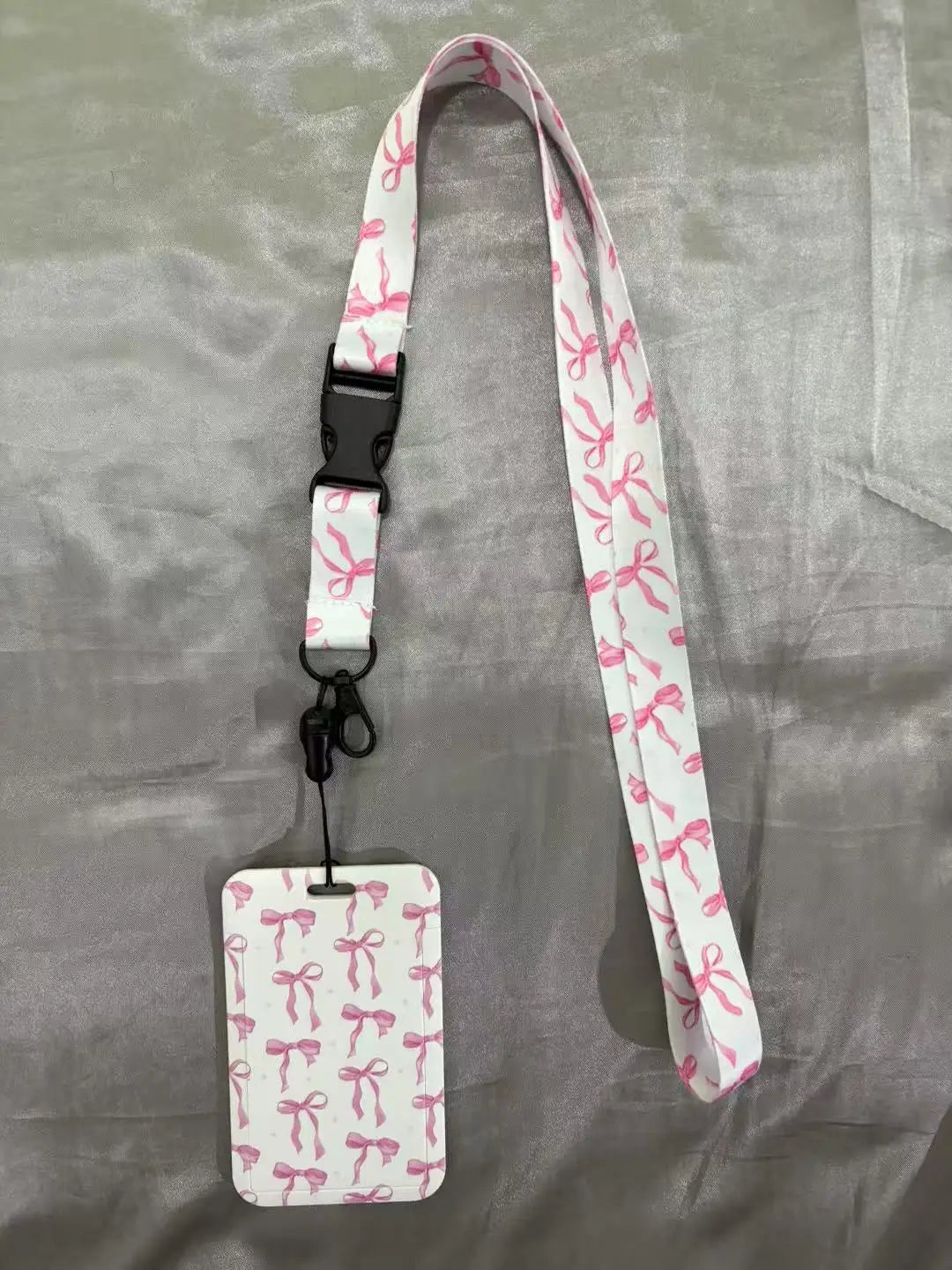 White lanyard with pink floral pattern attached to an ID badge holder.