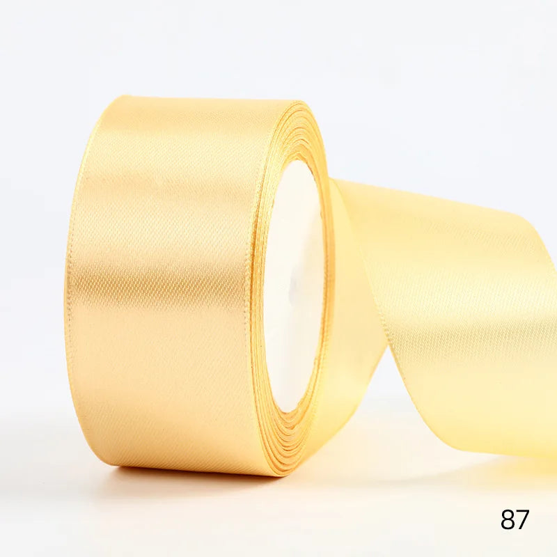 A roll of golden satin ribbon used for gift wrapping and DIY crafts.