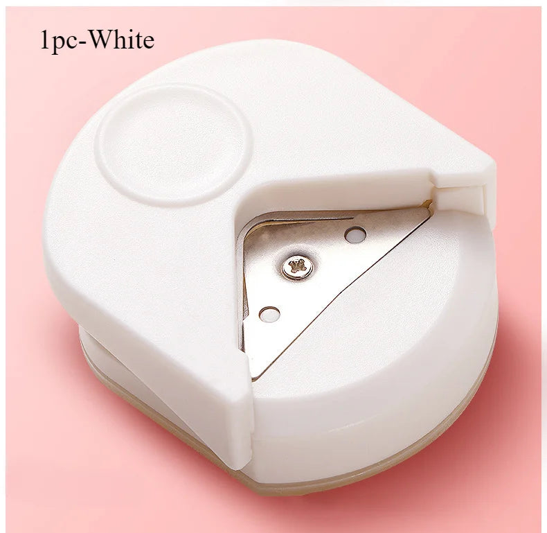 A white precision corner cutter tool is shown, featuring a round opening and a metal blade for cutting paper and cardstock.
