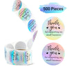 A roll of 500 rainbow laser thank you stickers for gifts and packaging