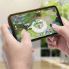 A hand holds a smartphone displaying a mobile game, with a braided USB charging cable visible.