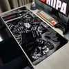 A large black and white anime design mouse pad featuring a fierce berserk character and an owl head on a desk.