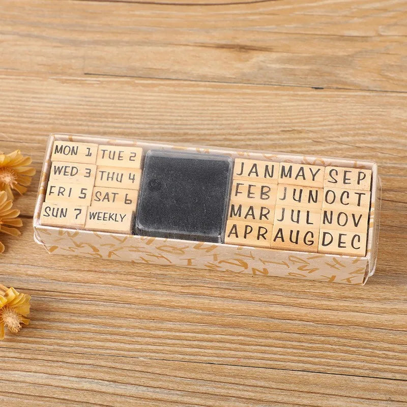 A wooden stamp seal set with monthly and weekly labels arranged in a rectangular box on a light wooden surface.