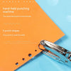 A close-up of a silver handheld punching machine with various punch shapes resting on an orange background.