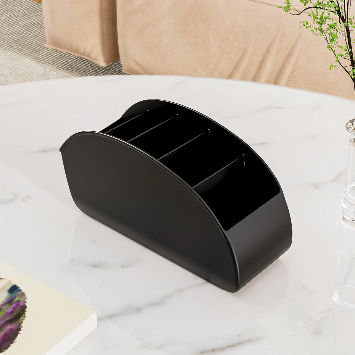 A black acrylic remote control holder and desk organizer tray resting on a white marble surface.
