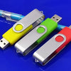 Three metal USB 2.0 flash drives in yellow, green, and red are displayed on a blue surface.