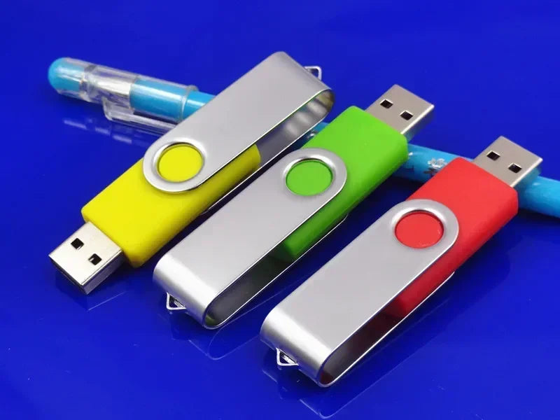 Three metal USB 2.0 flash drives in yellow, green, and red are displayed on a blue surface.