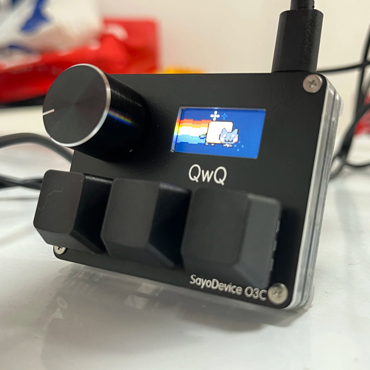 A black magnetic rapid trigger keyboard switch device labeled QwQ, featuring a blue display and a silver body.