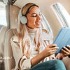 A woman is using a blue Stylish Case for iPad on her tablet inside an airplane cabin.