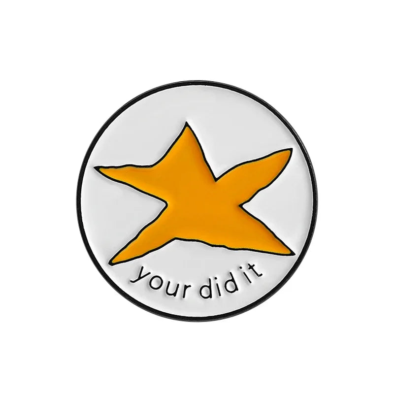 An enamel pin featuring a yellow star design on a white circular background with the text your did it.