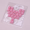 Eine Sammlung rosa Schmetterlings-Keycaps und ein weißer Ring in einer klaren Kunststoffschale.